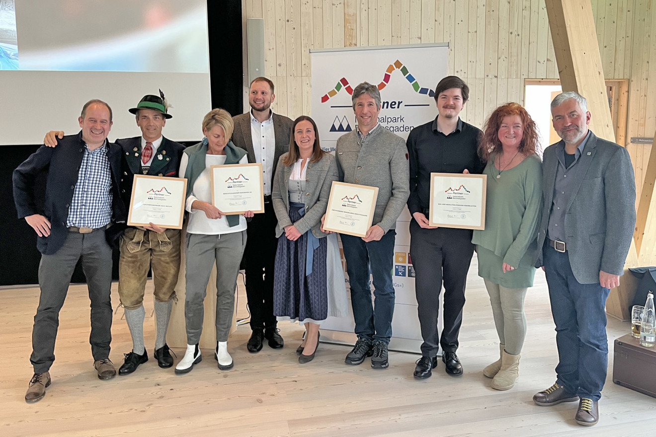 Neun Personen, darunter die neuen Partner posieren mit Urkunden für ein Gruppenbild.
